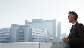 Man in business attire looking out to a city skyline